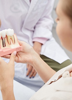 A dental patient holding an enlarged dental implant model