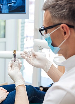 A male dentist showing a dental implant to his female patient 