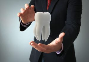 Dentist in Enterprise holding a tooth.