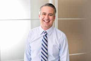 man in dress shirt and tie smiling after seeing dentist in Enterprise 