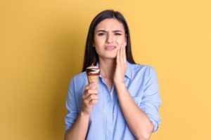 woman experiencing tooth sensitivity after eating ice cream 