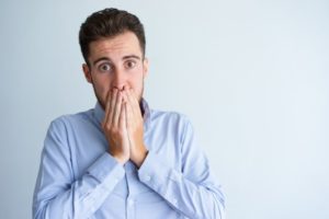 Man covers his mouth after learning about gum disease risk factors