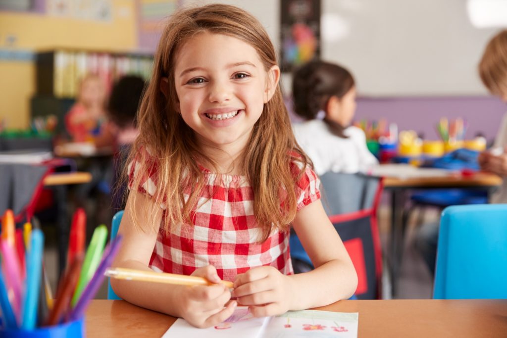 Child smiling while completing activity in classroom