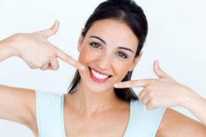 woman pointing to her smile after spending tax refund on dental care