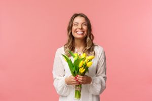 a woman with a beautiful smile holding spring flowers