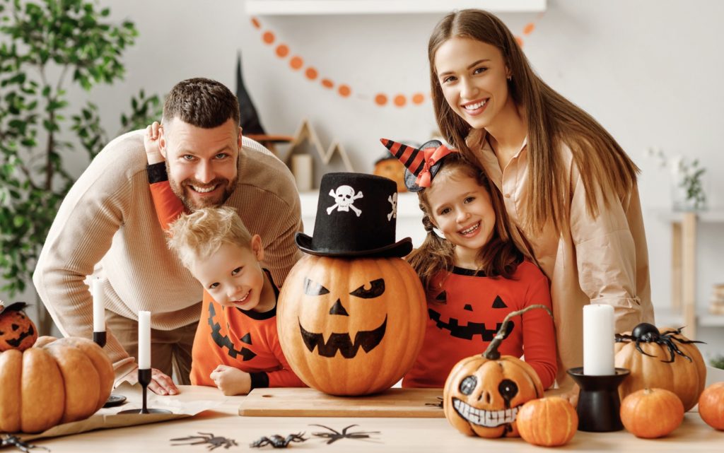 Family in coordinating outfits smiling with Halloween decor
