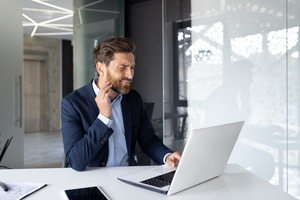Businessman suffering from a toothache while working on a laptop